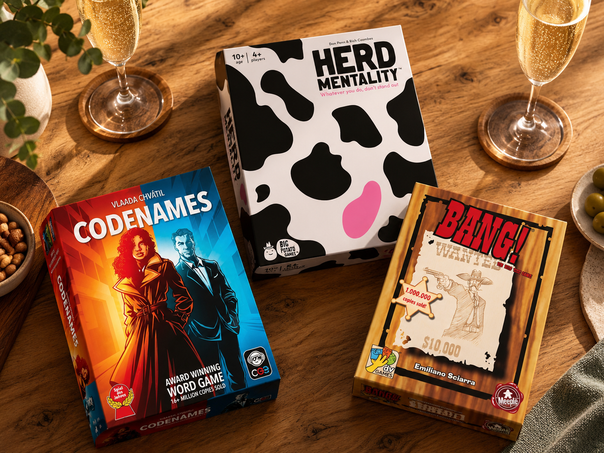 Herd Mentality, Codenames and Bang! on a timber table with drinks and snacks